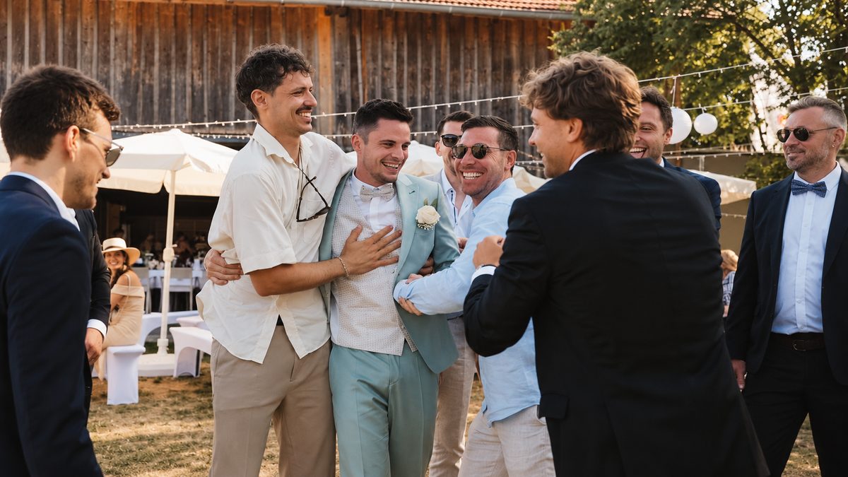 Freunde umringen lachend den Bräutigam